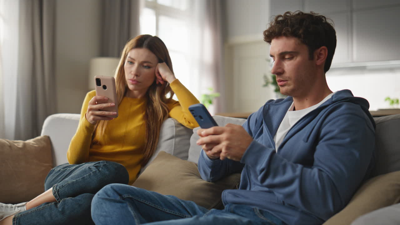 Addicted duet browsing internet at sofa closeup. Couple ignoring each other