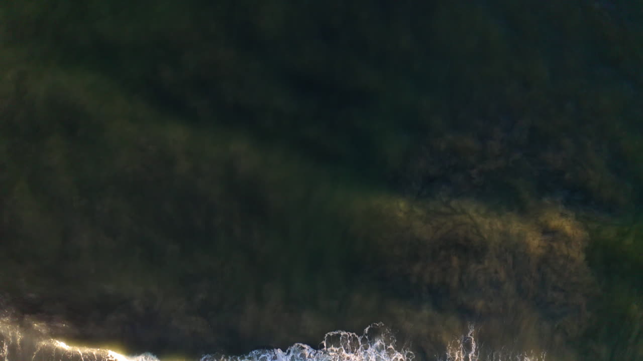 Dynamic Aerial View of Ocean Waves Crashing on a Sandy Beach