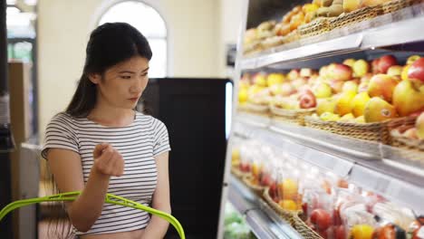 an asian shop visitor chooses fruits and vegetables in special packages. hold a basket in your hands