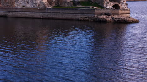 una toma de avión no tripulado que muestra las ruinas del castillo de koknese a lo largo del río daugava con hermosos reflejos en el agua.