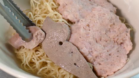 thai styled tom yum noodles contained with egg noodles, minced pork cake, pork liver and intestine, bean sprouts, spices and grounded peanut, one of the favourite street food in thailand