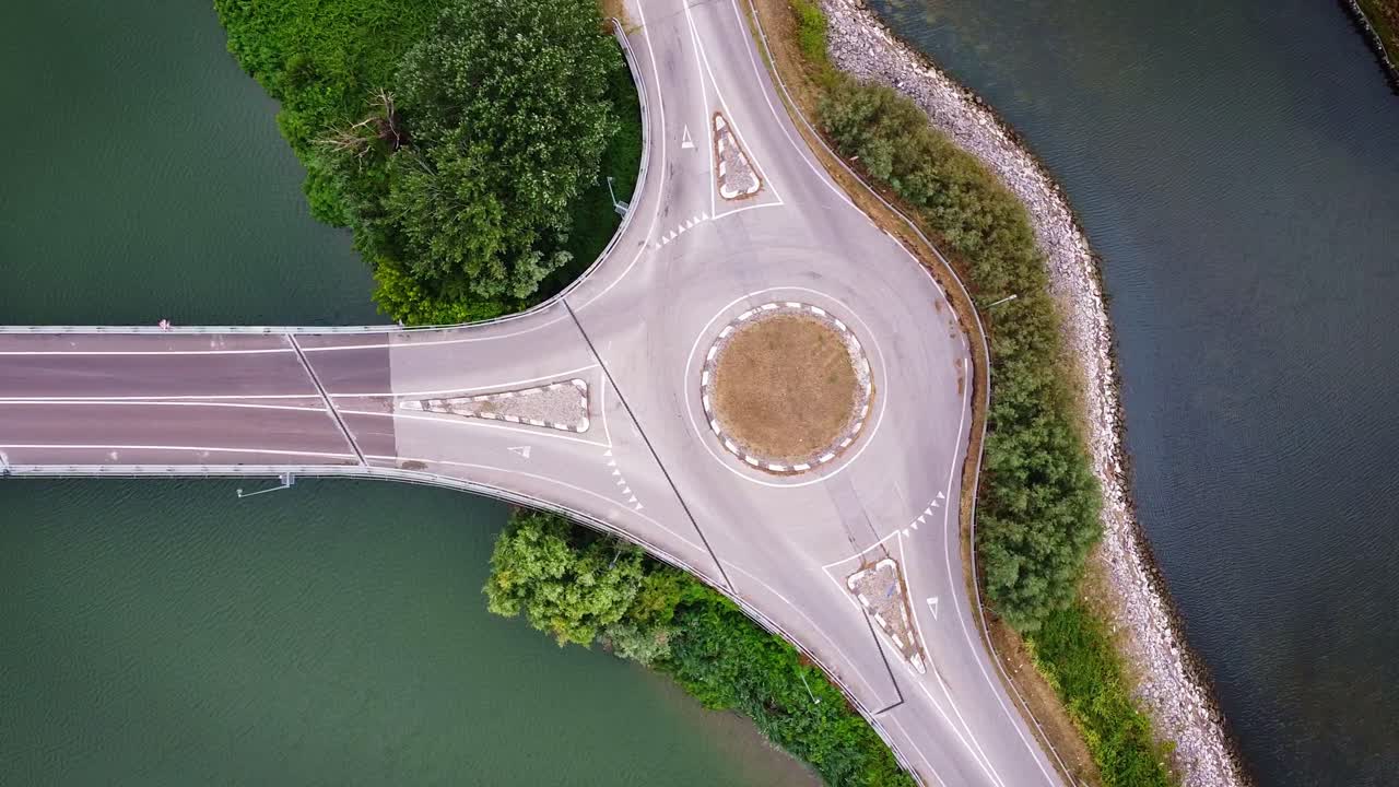 Top-down drone view of roundabout surrounded by water canals and greenery in Marina di Ravenna, Italy, scenic traffic flow and road patterns from above