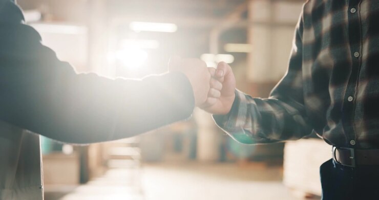 Two Men Fist Bumping in a Warehouse Setting