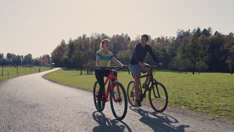 young man and a girl enjoying cycling in nature on a sunny autumn day, tracking