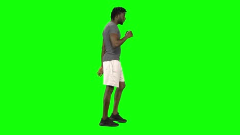 african american man walking and drinking coffee at green screen, chroma key. profile view