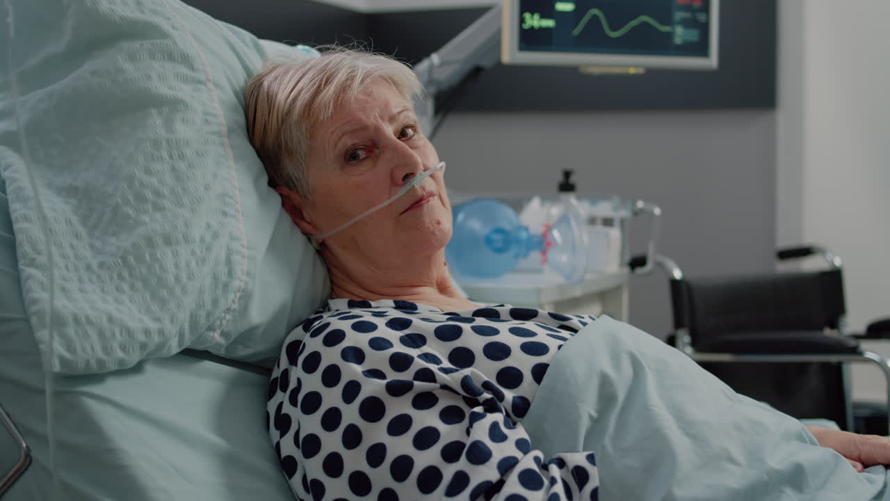 Portrait of old patient laying in bed with nasal oxygen tube