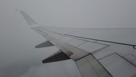 view of a plane wing going through clouds and fog