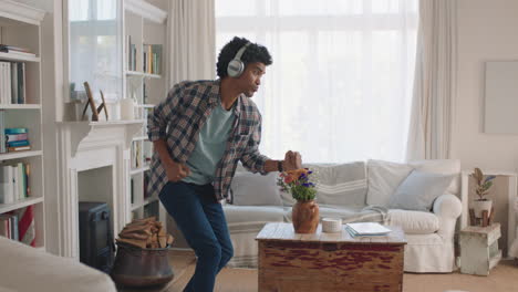 joven feliz bailando en casa celebrando el éxito escuchando música usando auriculares divirtiéndose bailando en la sala de estar el fin de semana