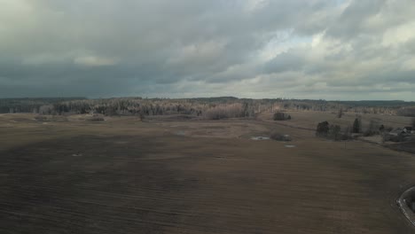 Aerial-forward-over-wasteland-with-forest-in-background