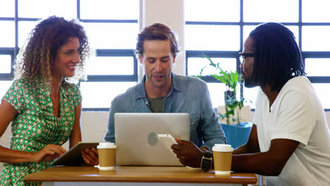 colleagues discussing with each other over laptop