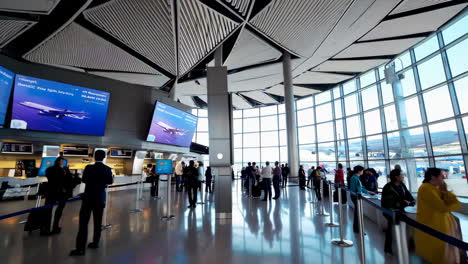 airport terminal with large flight information display and passengers