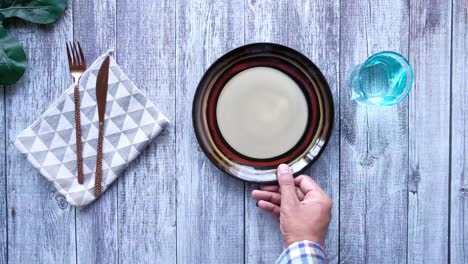 top view of person hand putting empty plate on table