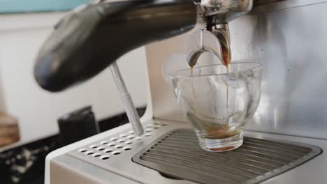 primer plano del café que se vierte en la taza de la máquina de café en la cafetería, cámara lenta
