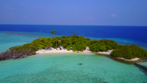 island in hawaii - lush crescent-shaped island on white sand surrounded by bright blue shallow sea water - wide shot