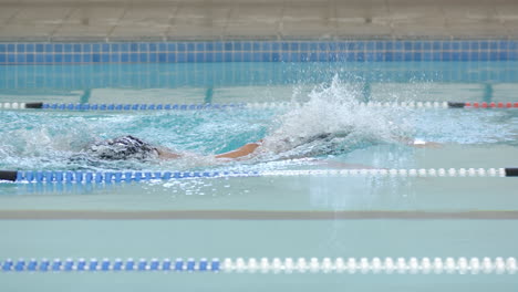 swimming freestyle in pool, male athlete training for competition in swim lane