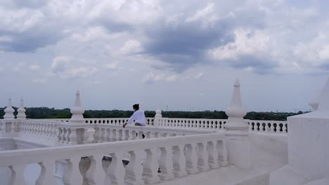 Woman-walks-along-roof-top-balustrade-on-Leon-Cathedral,-cloudy-sky