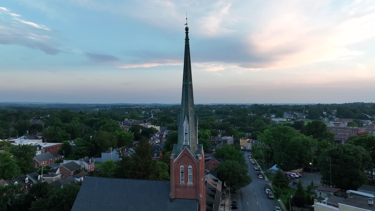 American church in suburb neighborhood of American town at dusk. Aerial orbit shot of houses and homes betweem Green trees in summer. Pennsylvania, USA
