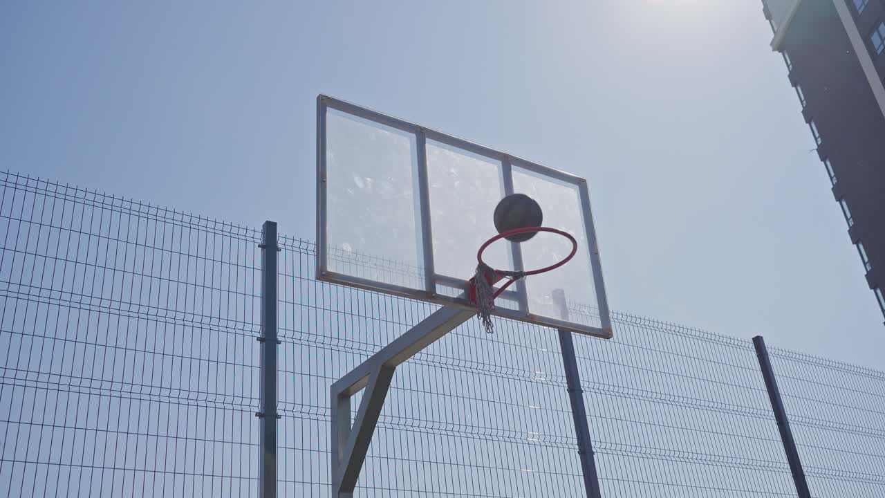 Uomo atletico che fa canestro su un campo da basket all'aperto
