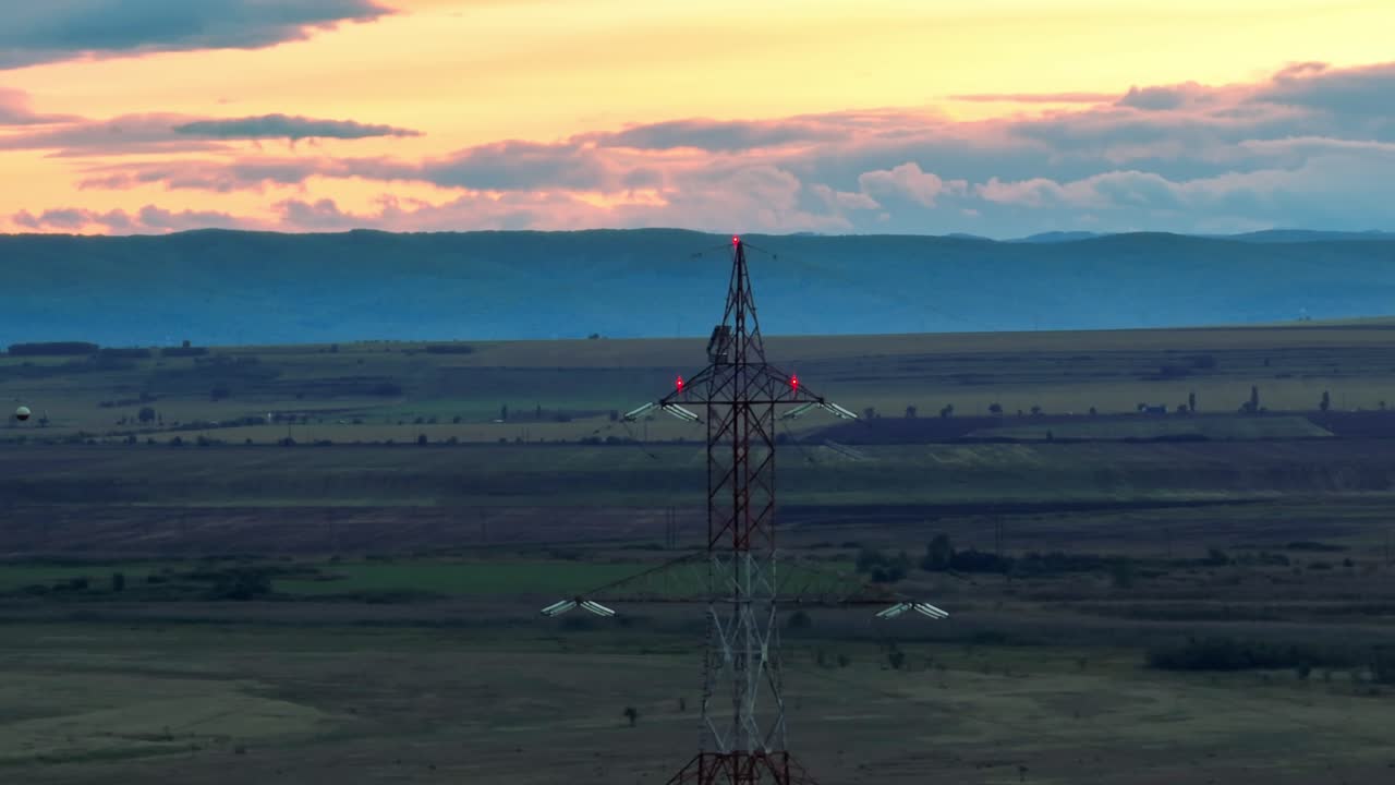 восходящий аэрофотоснимок опоры лэп на фермерских полях перед горным хребтом