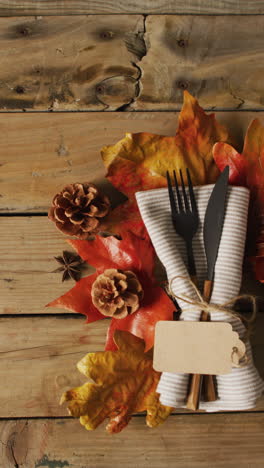 vídeo vertical de cubiertos, tela, hojas de otoño y conos sobre una superficie de madera