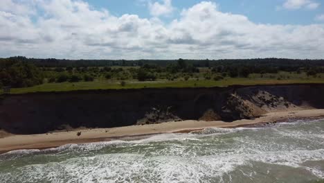 Volando-Sobre-La-Costa-Del-Mar-Báltico-Ulmale-Seashore-Bluffs-Cerca-De-Pavilosta-Letonia-Y-Deslizamientos-De-Tierra-Con-Una-Cueva-Ondulada-Cubierta-De-Rocas-Y-Acantilados-Salpicados