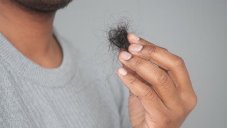 man holding clump of hair in hand