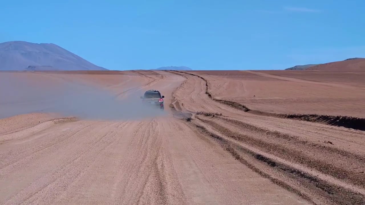 Perspectiva de carro dirigindo em uma trilha off-road empoeirada através de uma paisagem árida de estepe andina. Vista panorâmica da natureza selvagem de alta altitude na Bolívia perto de Uyuni