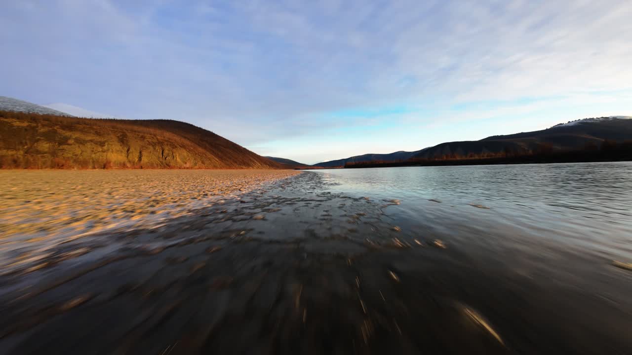 Experience the breathtaking wilderness of Yakutia as a drone glides above tranquil rivers and picturesque mountains. The stunning natural beauty unfolds in vibrant colors and expansive views.
