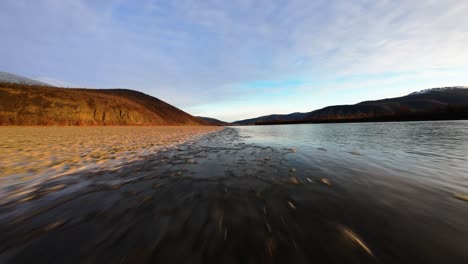 experience the breathtaking wilderness of yakutia as a drone glides above tranquil rivers and picturesque mountains. the stunning natural beauty unfolds in vibrant colors and expansive views.