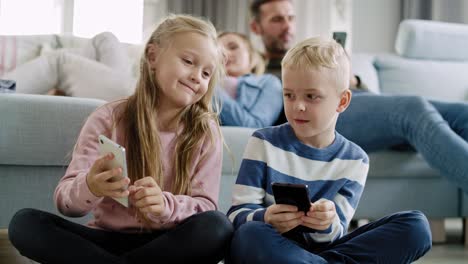 handheld view of children using mobile phone in living room