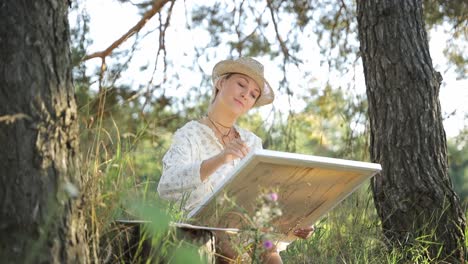 beautiful and talented artist paints a picture on an easel