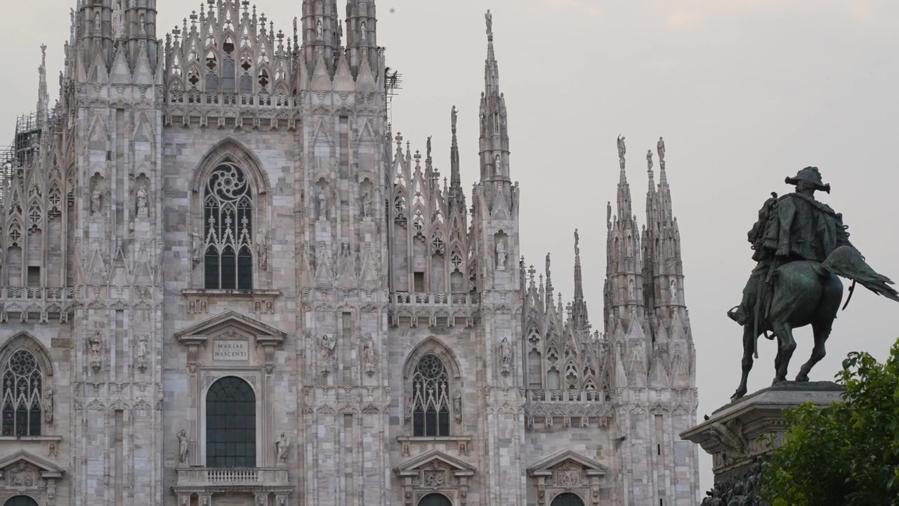 Monumento a Vittorio Emanuele II frente al Duomo de Milán, con fachada gótica y agujas imponentes con vistas a la Piazza del Duomo. Hito histórico que domina el centro de Milán, Italia, durante la noche