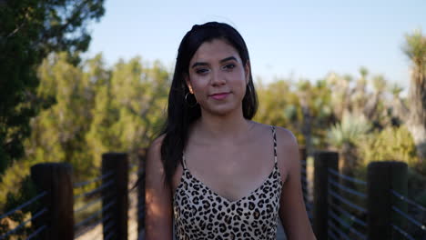 a beautiful young hispanic woman walking and smiling on a nature path in slow motion in sunset light