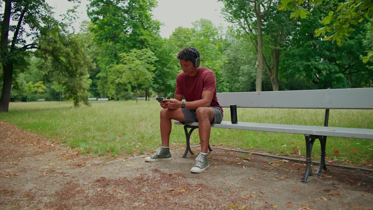 Man listening to music on bench in park