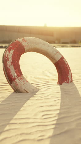 old life preserver on a sandy shore at sunset