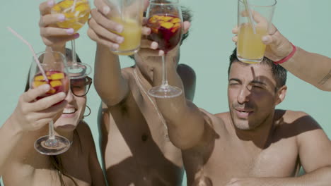 medium shot of happy teenagers clinking glasses in swimming pool