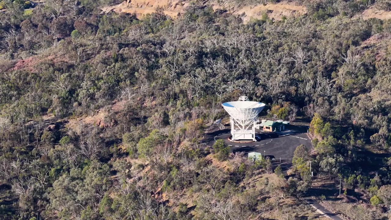 Laaja ilmakuva tieteellisestä radioteleskooppiantennista australialaisessa eukalyptusmetsämaisemassa