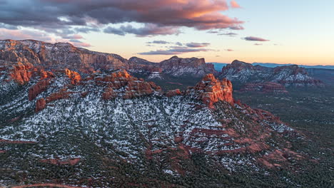 red rock mountains and buttes in sedona partly covered with snow at sunset