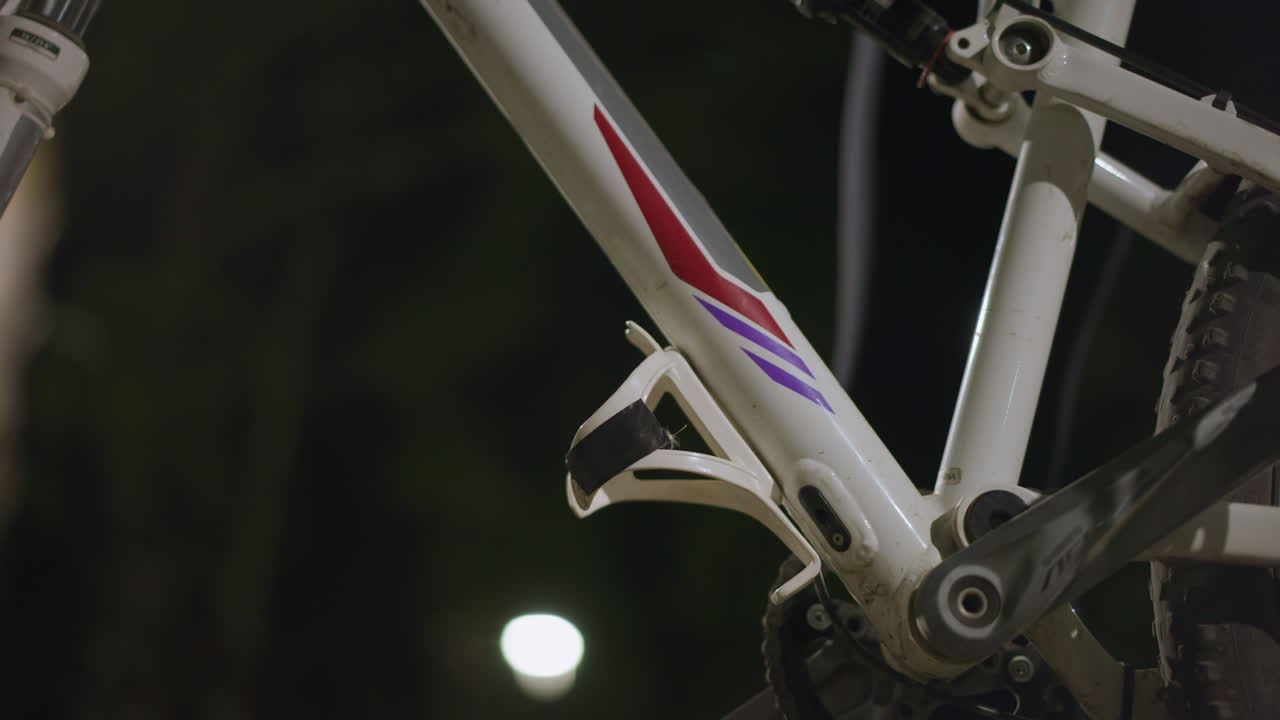 Closeup Showing Hand Placing Container On Bike, Precise Hand Placement Of Bottle Into Bicycle Cage Structure, Detailed View Of Hand Carefully Fitting Bottle Into Bicycle Holder With Steady Grip