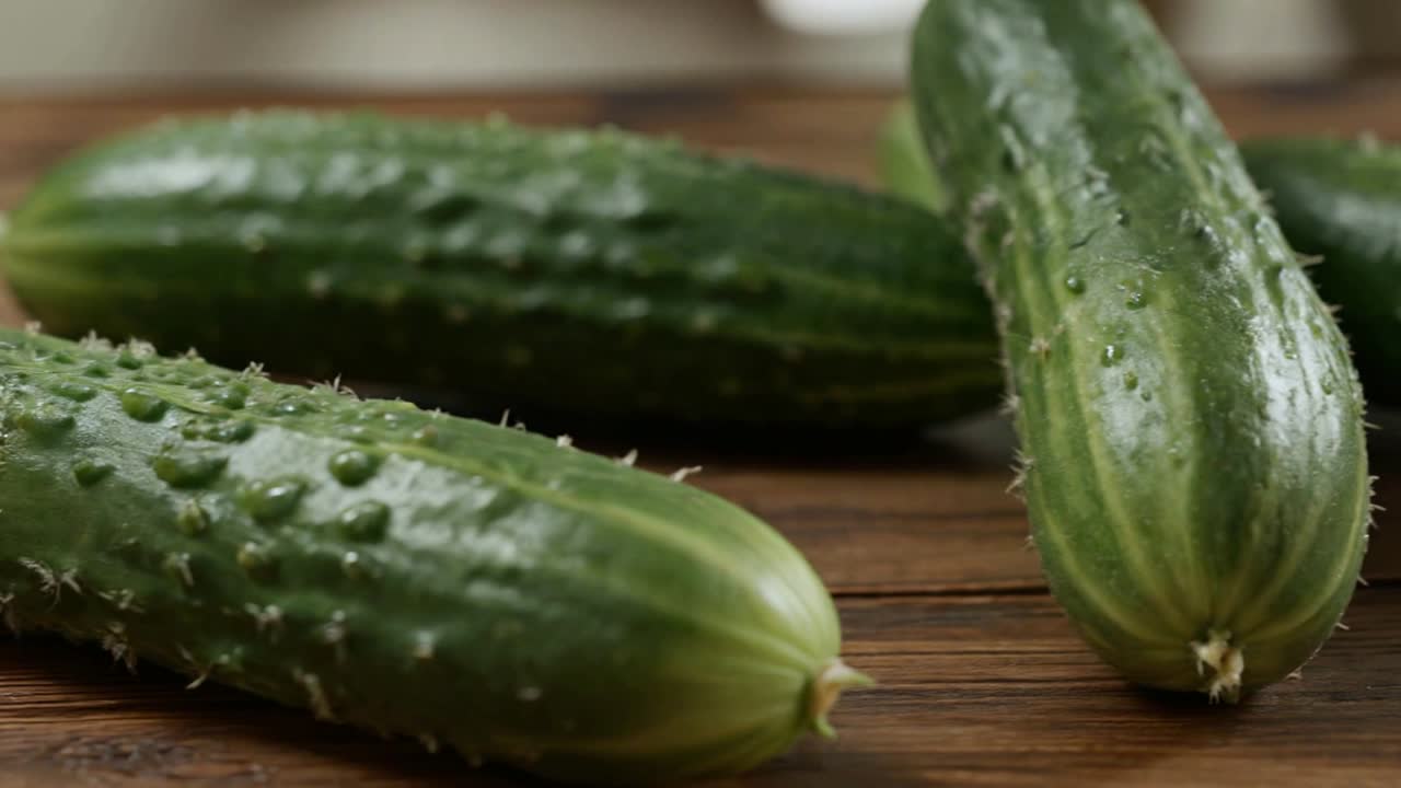 Ferske grønne agurker med vanndråper på et trebord