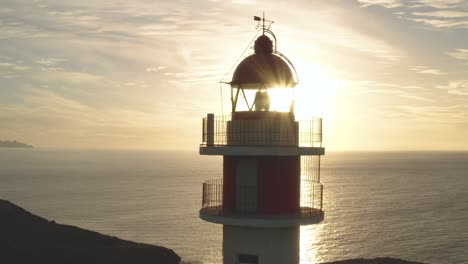 Nahaufnahme-Einer-Drohnenaufnahme-Eines-Leuchtturms-Mit-Sonne-Und-Meer-Im-Hintergrund-Zur-Goldenen-Stunde