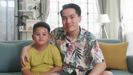 asian father and his son are watching tv at home