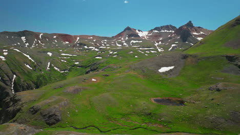 aerial drone cinematic high altitude ice lake basin island lake trail lush green hike silverton ouray red mountain pass colorado dreamy heavenly rockies scene summer peaks forward motion