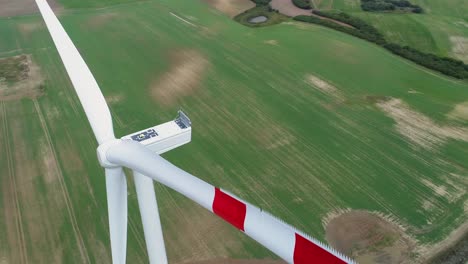 Top-View-Of-Farm-Windmill-Not-Spinning-On-Greenfields-In-Kwidzyn,-Poland---Painted-In-White-With-Red-Marks-On-Blades---Drone-Pan-Left