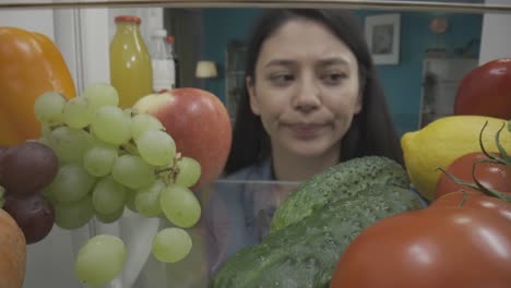 woman looking disappointed in a full refrigerator