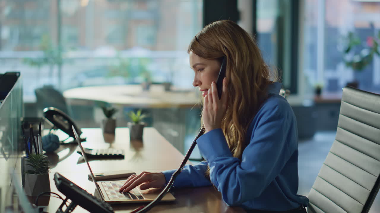 Unternehmerin beantwortet einen Telefongespräch und tippt auf einem Laptop im Büro