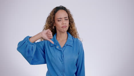 Thumbs-down,-face-and-hands-of-woman-in-studio