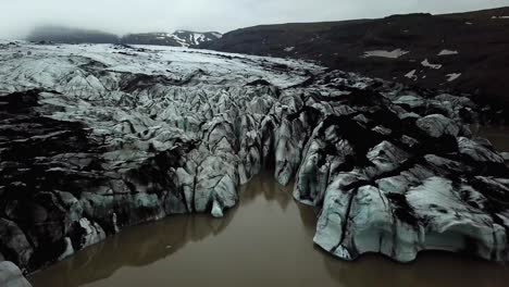 Vista-Aérea-Del-Paisaje-Sobre-El-Glaciar-Sólheimajökull,-Derritiéndose-En-El-Agua,-Durante-El-Verano,-Islandia