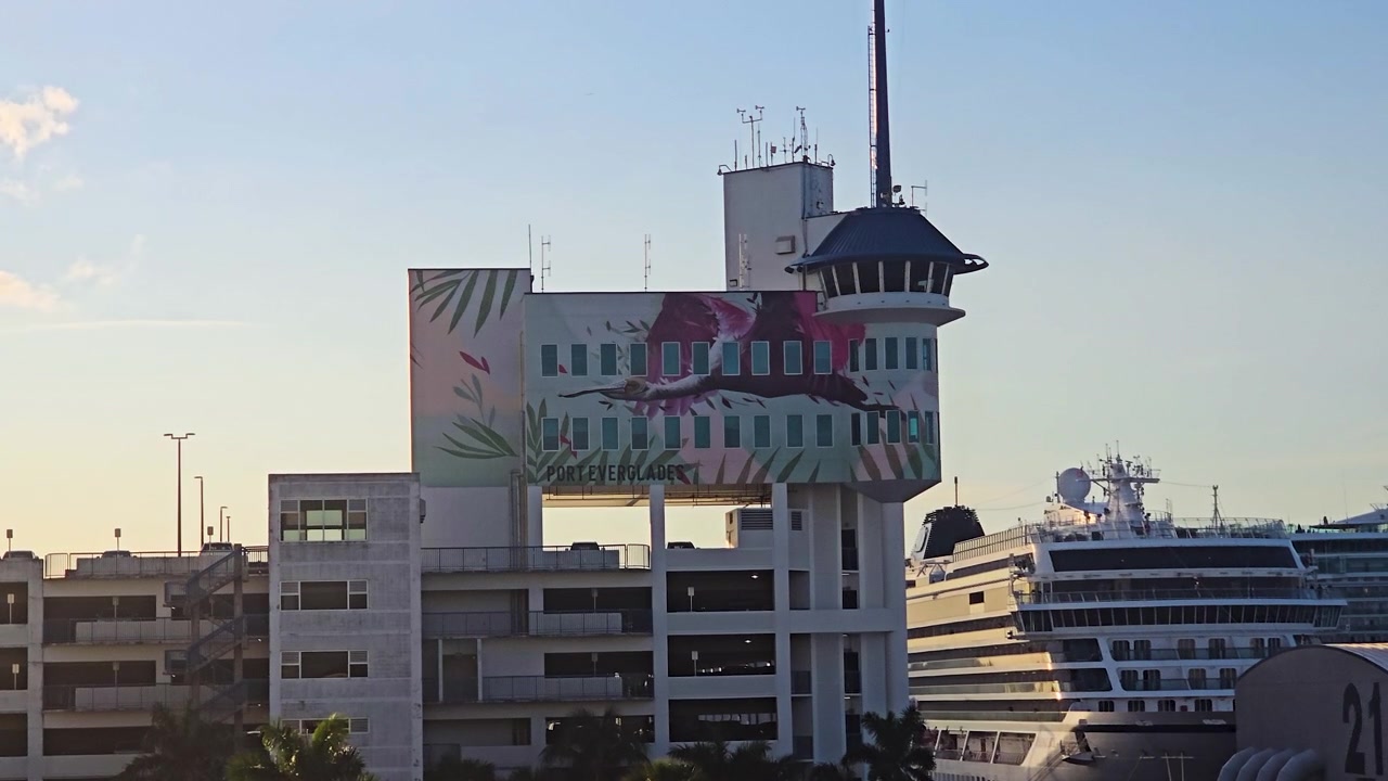La Torre del Capitano di Porto con un grande murale dipinto sopra un parcheggio multipiano, con un'enorme nave da crociera di lusso ormeggiata al terminal di Port Everglades a Fort Lauderdale, Florida, in un pomeriggio di sole.