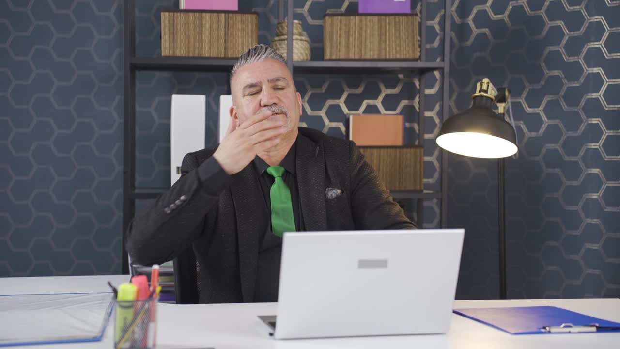 Sleepy businessman yawns looking at camera.